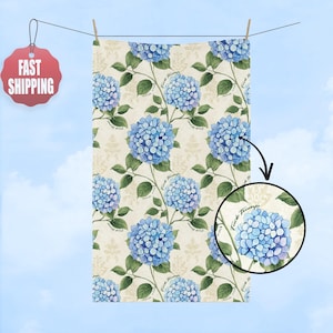May include: A rectangular towel with a repeating pattern of blue hydrangea flowers and green leaves on a cream background. The words "Fuck Trump" are printed on the stems. The towel is hanging on a clothesline.