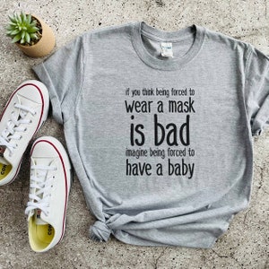 Puede incluir: Camiseta gris con el texto "if you think being forced to wear a mask is bad imagine being forced to have a baby".