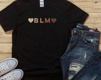 May include: Black t-shirt with the text "BLM" in brown letters and two hearts on either side of the letters. The hearts are brown, light brown, and beige.