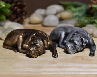 May include: Two sleeping dog figurines, one in a bronze finish and the other in a silver finish. The figurines are made of resin and are detailed with realistic features.