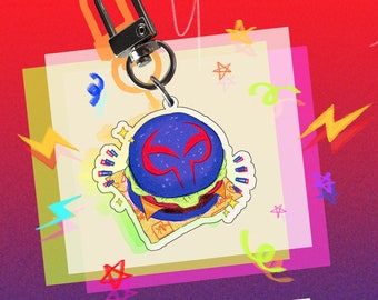 Puede incluir: Un charm de Spider-Man en forma de hamburguesa, de color azul y rojo. El charm está unido a un llavero plateado. El texto "SPIDEYVERSE: MIGUEL CHARMS *LIMITED QUANTITIES*" está escrito debajo del charm.