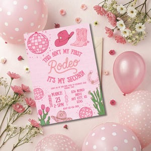 Pode incluir: Convite rosa com tema de rodeio, com ilustra&ccedil;&otilde;es de chap&eacute;u de cowboy, botas e bola de discoteca. O texto diz "This Ain't My First Rodeo, It's My Second!" com detalhes do evento. Bal&otilde;es e flores rosas circundam o convite.