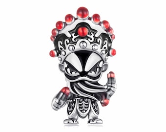 May include: A silver charm depicting a stylized figure in traditional Chinese opera attire. The charm features a detailed headdress with red accents, a black and white face, and ornate clothing. The figure is holding a small object in its hand.