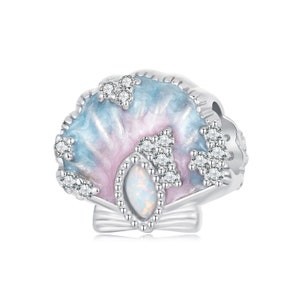 Pode incluir: Um berloque de prata em forma de concha com acabamento em esmalte iridescente rosa e azul. A concha tem uma pedra de opala branca no centro e é decorada com pedras de zircônia cúbica transparentes.