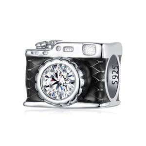 Peut inclure: Un charme en argent en forme d'appareil photo noir avec un objectif en cristal transparent. Le charme porte l'inscription "S925" sur le côté.