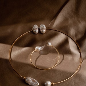 May include: Two gold necklaces with baroque pearls. The larger necklace has two large pearls and the smaller necklace has one large pearl and one smaller pearl.