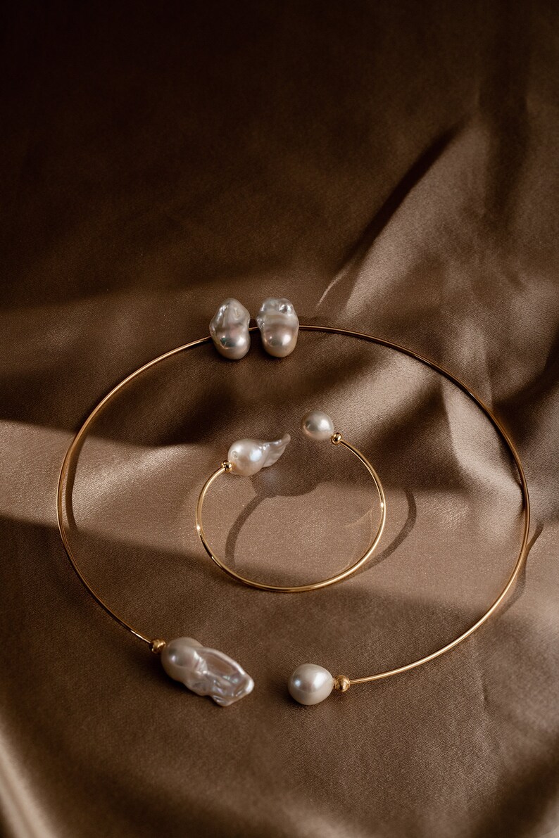 May include: Two gold necklaces with baroque pearls. The larger necklace has two large pearls and the smaller necklace has one large pearl and one smaller pearl.