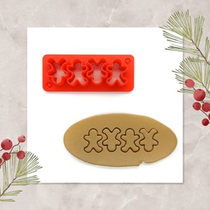 May include: A red plastic gingerbread man cookie cutter with four individual cutters. The cutter is shown next to a brown oval of cookie dough with four gingerbread men cut out.