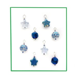 May include: Assortment of eight blue and clear glass ornaments with silver metal accents. The ornaments are shaped like stars and spheres.