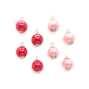 May include: A set of eight pearl-like ornaments with silver wire loops. The ornaments are in two colors: pink and red.