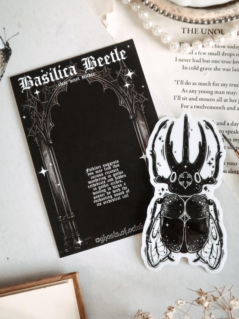 May include: Black and white sticker of a beetle with a gothic archway background. The sticker has the text "Basilica Beetle" and "Folklore suggests you may find this curious creature wandering in gothic cathedrals and hidden in gothic arches. waiting to bless a passer by with the enchanting sound of its orchestral call."