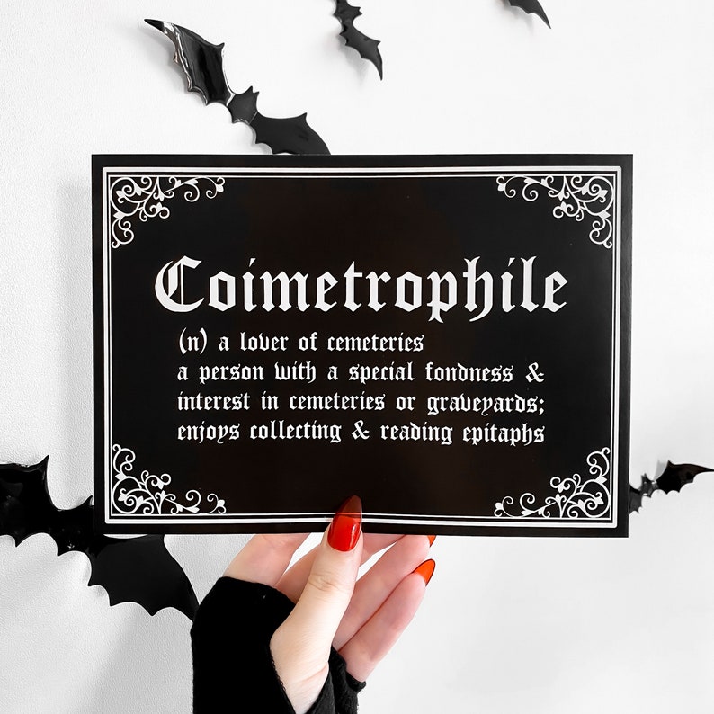 Puede incluir: Impresi&oacute;n en blanco y negro con la palabra "Coimetrophile" en fuente g&oacute;tica. La impresi&oacute;n define la palabra como "un amante de los cementerios" y describe a una persona que disfruta visitando cementerios y leyendo epitafios.