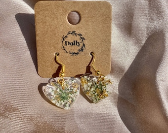 Pendientes de corazón de resina con flores prensadas y escamas metálicas.