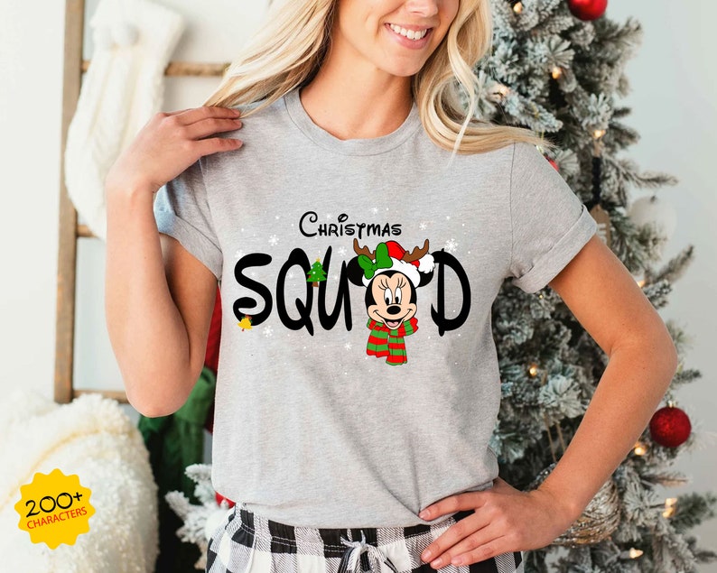 May include: Gray t-shirt with a Christmas-themed design featuring Mickey Mouse wearing a Santa hat and reindeer antlers. The text "Christmas Squad" is printed in black with a white outline.