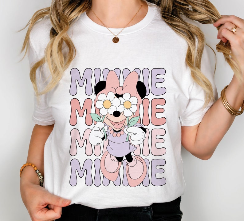 May include: White t-shirt with a graphic of Minnie Mouse wearing flowers over her eyes. The text "MINNIE" is repeated four times in a retro font.