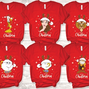 May include: Six red t-shirts with a Christmas theme featuring characters from Beauty and the Beast. The shirts feature Belle, the Beast, Lumiere, Mrs. Potts, Chip, and Cogsworth wearing Santa hats and reindeer antlers. Each shirt says "Merry Christmas".