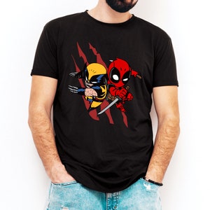 May include: Black t-shirt with a graphic of Wolverine and Deadpool in a cartoon style. The graphic features a red and black color scheme with a yellow and brown Wolverine.