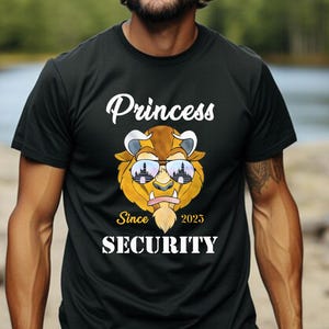 May include: Black t-shirt with a white graphic of a cartoon beast wearing sunglasses. The text "Princess" is above the beast and "Since 2025 Security" is below.