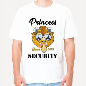 Op de afbeelding: Wit T-shirt met een cartoon afbeelding van een beest dat een zonnebril draagt met een kasteelreflectie. De tekst "Princess Since 2025 Security" is op het T-shirt gedrukt.