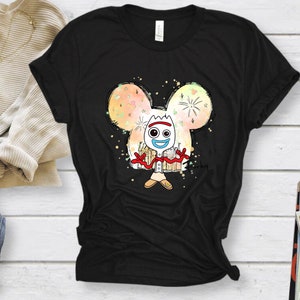 May include: Black t-shirt with a white cartoon character of Forky from Toy Story. Forky is standing in front of a colorful Mickey Mouse head with fireworks and stars. The text "Forky" is written in the bottom right corner.