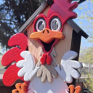 May include: A whimsical, wooden rooster-shaped birdhouse. The birdhouse features a red comb, wattle, and wings, with a white body and orange beak and feet. The birdhouse has a small, wooden roof.