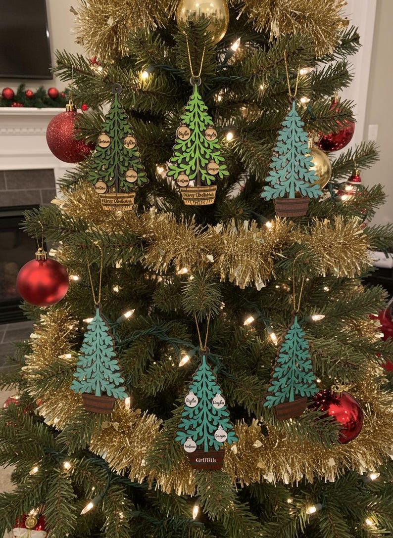 May include: Christmas tree ornaments in the shape of trees, hanging on a decorated Christmas tree. The ornaments are green and teal with family names on them. The ornaments are in a brown pot with the words "Merry Christmas" on them.
