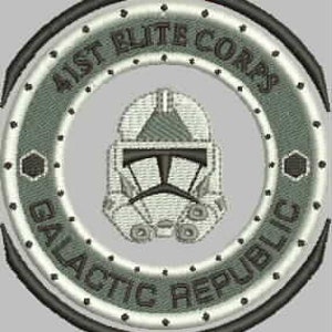 May include: A circular patch with a gray and white helmet in the center. The helmet has a white visor and a gray faceplate. The text "41st Elite Corps Galactic Republic" is written in a circle around the helmet.