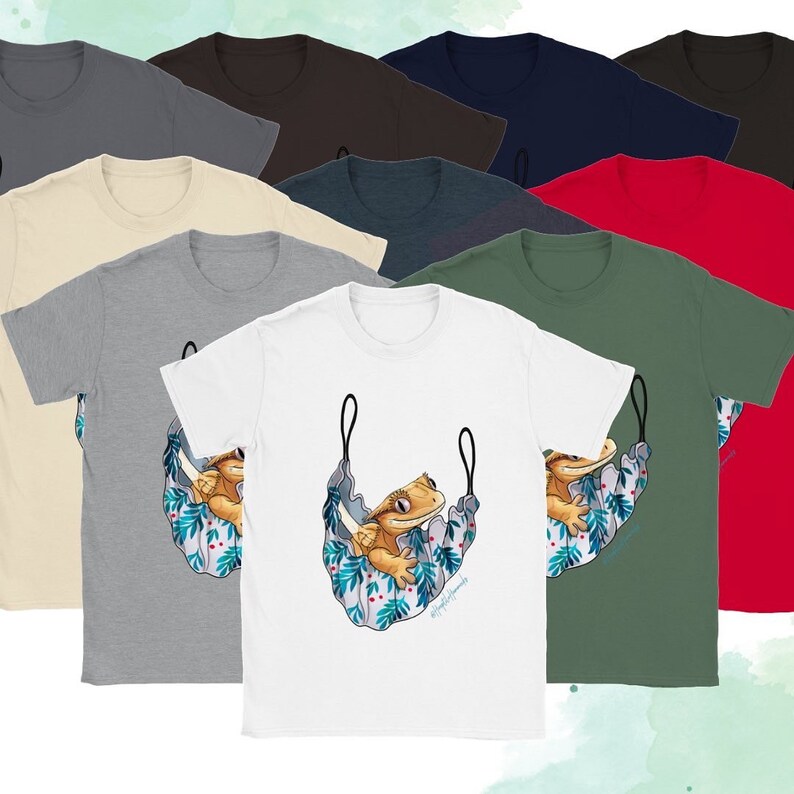 May include: A set of ten t-shirts featuring a cartoon illustration of a crested gecko in a hammock. The t-shirts are available in a variety of colors, including black, navy blue, red, brown, beige, gray, and green.