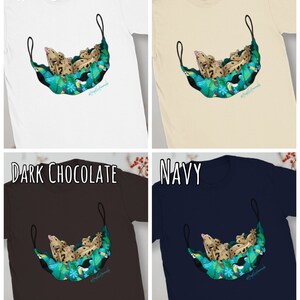 May include: White, natural, dark chocolate, and navy t-shirts. Each shirt features a graphic of a gecko in a hammock with toucans and tropical foliage. The text "#reptilemoments" is printed on the design.