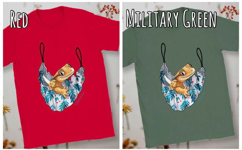 May include: A red and a military green t-shirt with a cartoon illustration of a crested gecko in a hammock. The gecko is light brown with a white belly and is sitting in a blue and white hammock with green leaves and red berries.