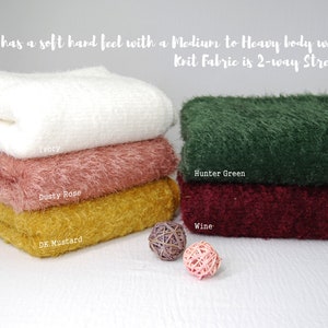 May include: Four stacks of soft, fuzzy fabric in ivory, dusty rose, dark mustard, and wine colors. The fabric is described as having a medium to heavy body weight and being 2-way stretch.