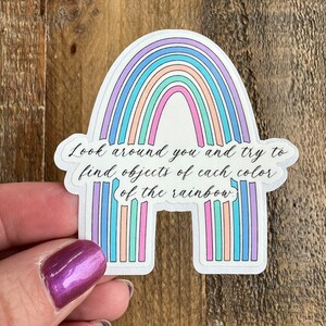 May include: A rainbow sticker with the text "Look around you and try to find objects of each color of the rainbow."