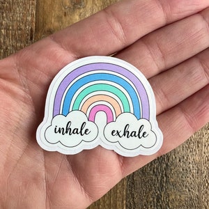 May include: A rainbow sticker with the words "inhale" and "exhale" in black script on white clouds.