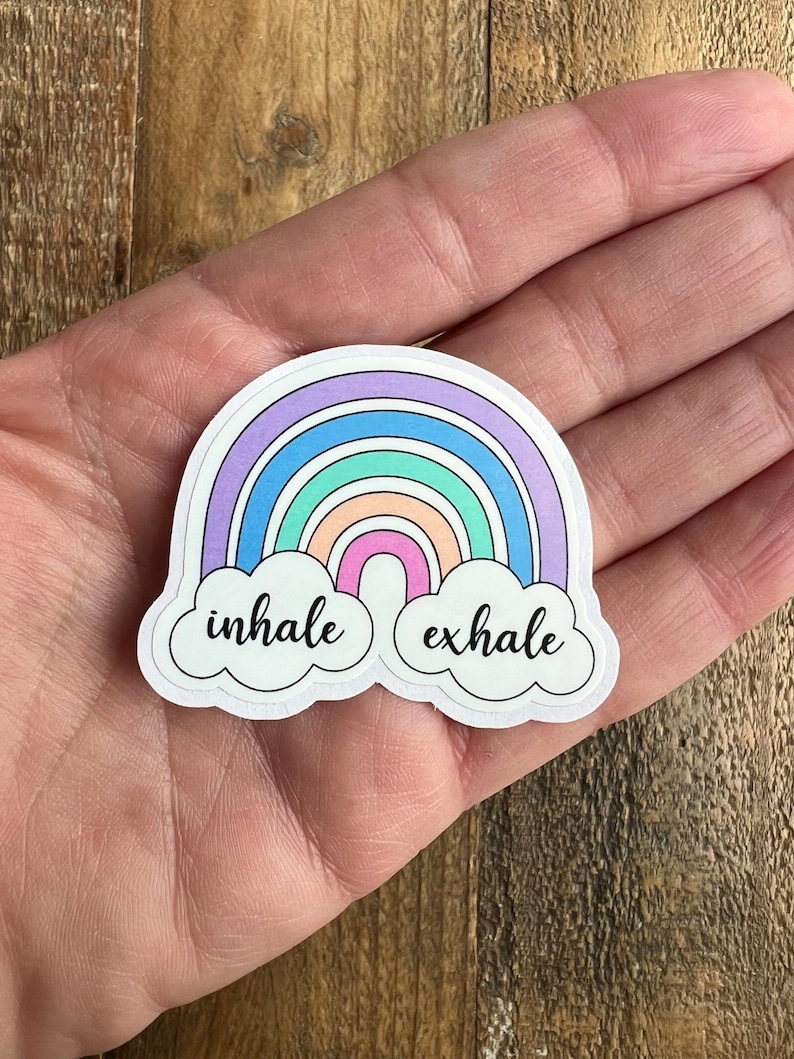 May include: A rainbow sticker with the words "inhale" and "exhale" in black script on white clouds.