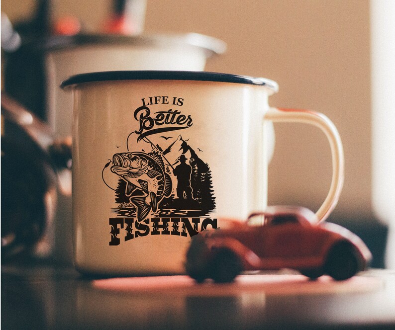 K&ouml;nnte beinhalten: Wei&szlig;e Emaille-Tasse mit einer schwarzen Grafik eines Fisches und dem Text "Life is Better Fishing".