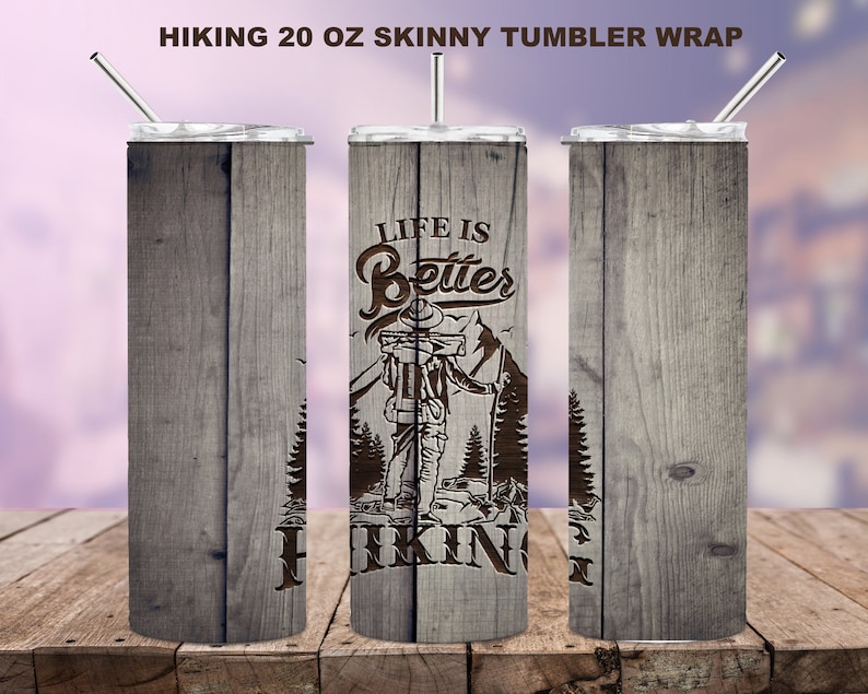 May include: A 20 oz skinny tumbler wrap with a wood grain design. The tumbler features the text "Life is Better Hiking" with an illustration of a hiker. The tumbler includes a silver lid and straw.