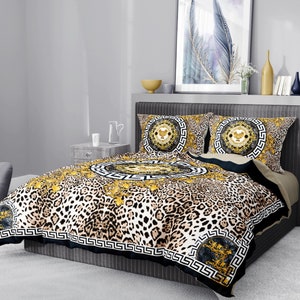 May include: A black and gold patterned bedding set with a leopard print design. The set includes a duvet cover, two pillowcases, and a decorative throw pillow.
