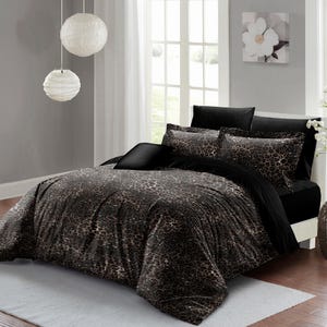 May include: A black and brown leopard print bedding set with black pillowcases. The bedding is on a bed with a white headboard and a white rug.
