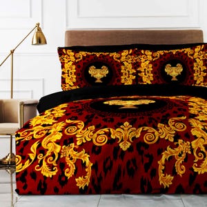 Op de afbeelding: Rode, zwarte en gouden beddengoedset met een barokpatroon met sierlijke gouden ontwerpen en een luipaardprint. De beddengoedset bevat een dekbedovertrek en twee kussenslopen.