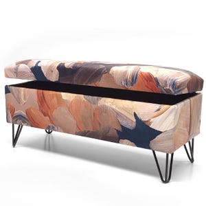 May include: A storage bench with a colorful abstract print fabric top and black hairpin legs. The lid is open, revealing the storage space inside.