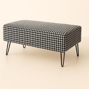 May include: A rectangular bench featuring a black and white houndstooth pattern. The bench has a padded top and is supported by four black hairpin legs. The design is a classic and stylish addition to any room.