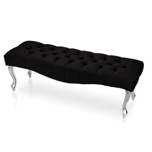 May include: A black velvet tufted bench with silver legs. The bench has a curved shape and is perfect for adding a touch of elegance to any room.