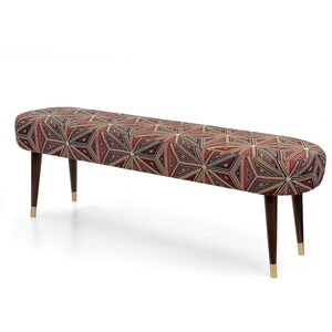 Op de afbeelding: Een gestoffeerde bank met een geometrisch patroon in tinten rood, bruin en goud. De bank heeft donkerbruine houten poten met goudkleurige uiteinden. De bank is ongeveer 152 cm lang.