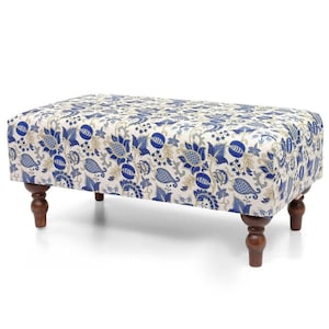 Può includere: Un pouf rettangolare con un motivo floreale blu, bianco e grigio. La parte superiore rivestita in tessuto poggia su quattro gambe in legno tornito marrone scuro. Un elemento d'arredo decorativo.