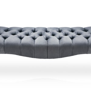 May include: A gray tufted bench with silver legs. The bench has a curved shape and a button tufted design.