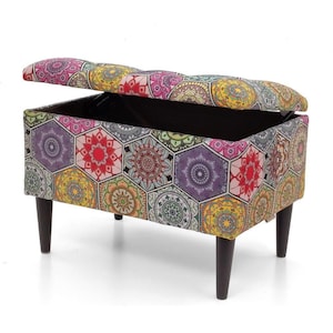 Può includere: Un pouf di stoccaggio colorato con un motivo geometrico che presenta esagoni e mandala. Il pouf ha un coperchio incernierato che si apre per rivelare un vano di stoccaggio.