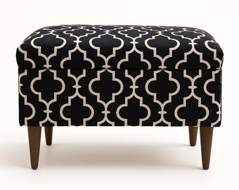 May include: A rectangular ottoman with a black and cream geometric pattern. The ottoman has four dark wooden legs. The top and sides are covered in a fabric with a repeating quatrefoil design.