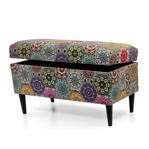 May include: A colourful storage bench with a geometric pattern. The bench has a hinged lid that opens to reveal storage space inside. The bench has black legs.