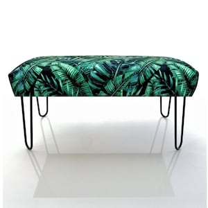 Peut inclure: Banc rectangulaire avec un motif de feuilles tropicales vertes et noires. Il est doté de pieds en épingle noirs. Ce banc d'intérieur offre une assise élégante et apporte une touche de nature à votre intérieur, mesurant environ 100 cm de long.