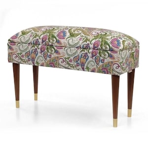 Könnte beinhalten: Dekorative Sitzbank mit Paisley-Muster in Grün-, Lila- und Blautönen auf cremefarbenem Hintergrund. Die Bank hat dunkelbraune Holzbeine mit goldfarbenen Spitzen. Die Bank hat eine ovale Form.